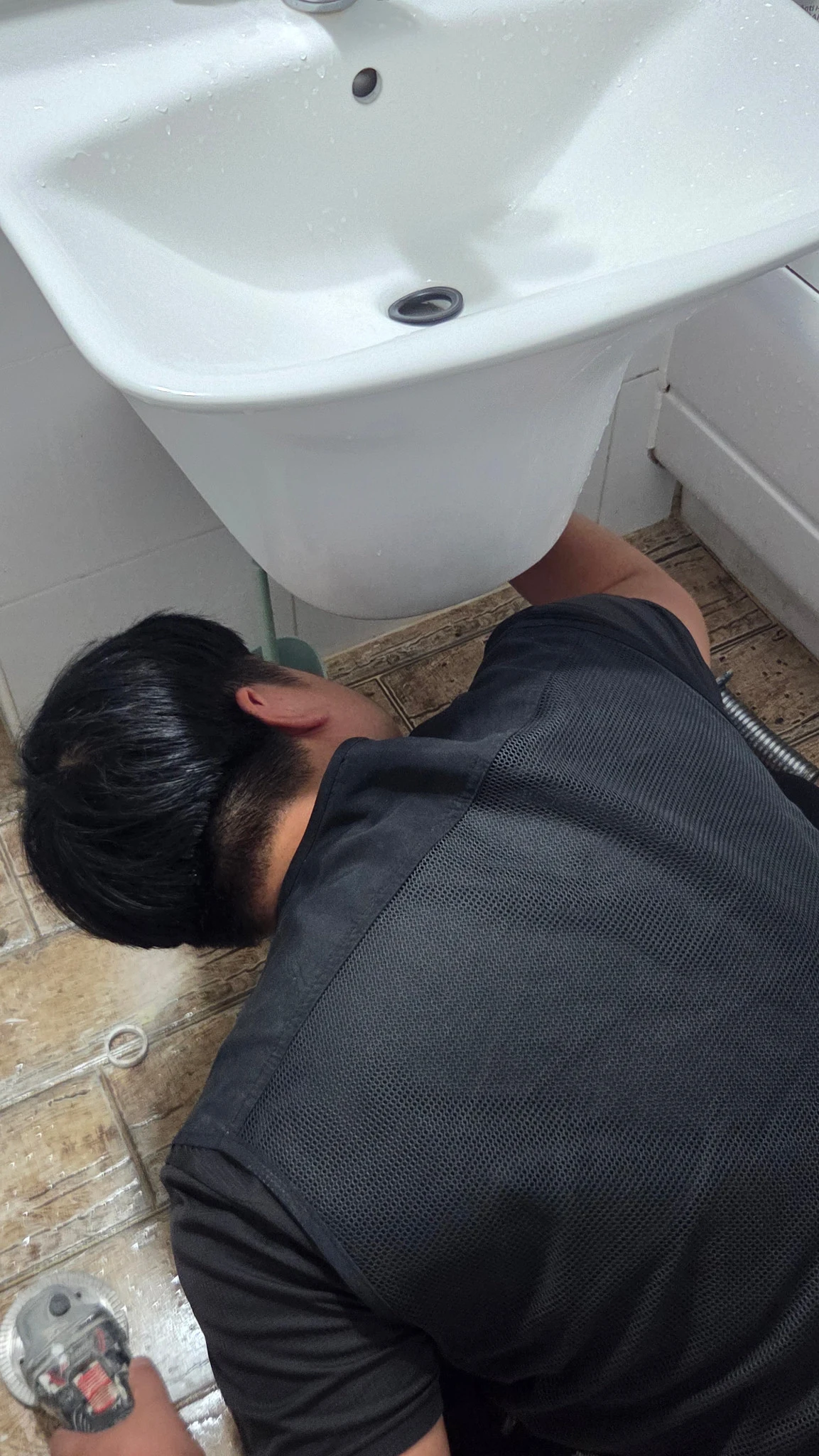 세면대 하부 배관을 가까이에서 점검하는 모습